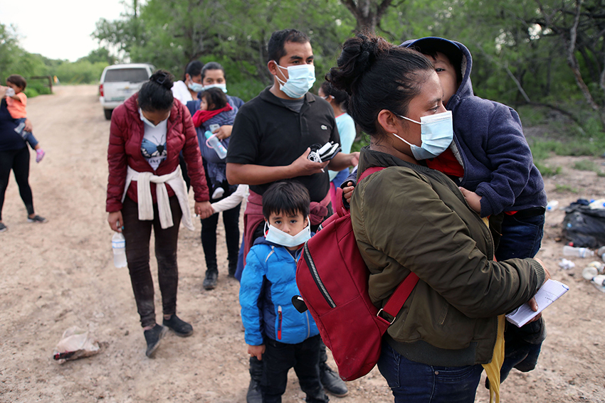 A Central American woman and her son who crossed the Rio Grande River to request asylum wait with other families to be processed by the Border Patrol.